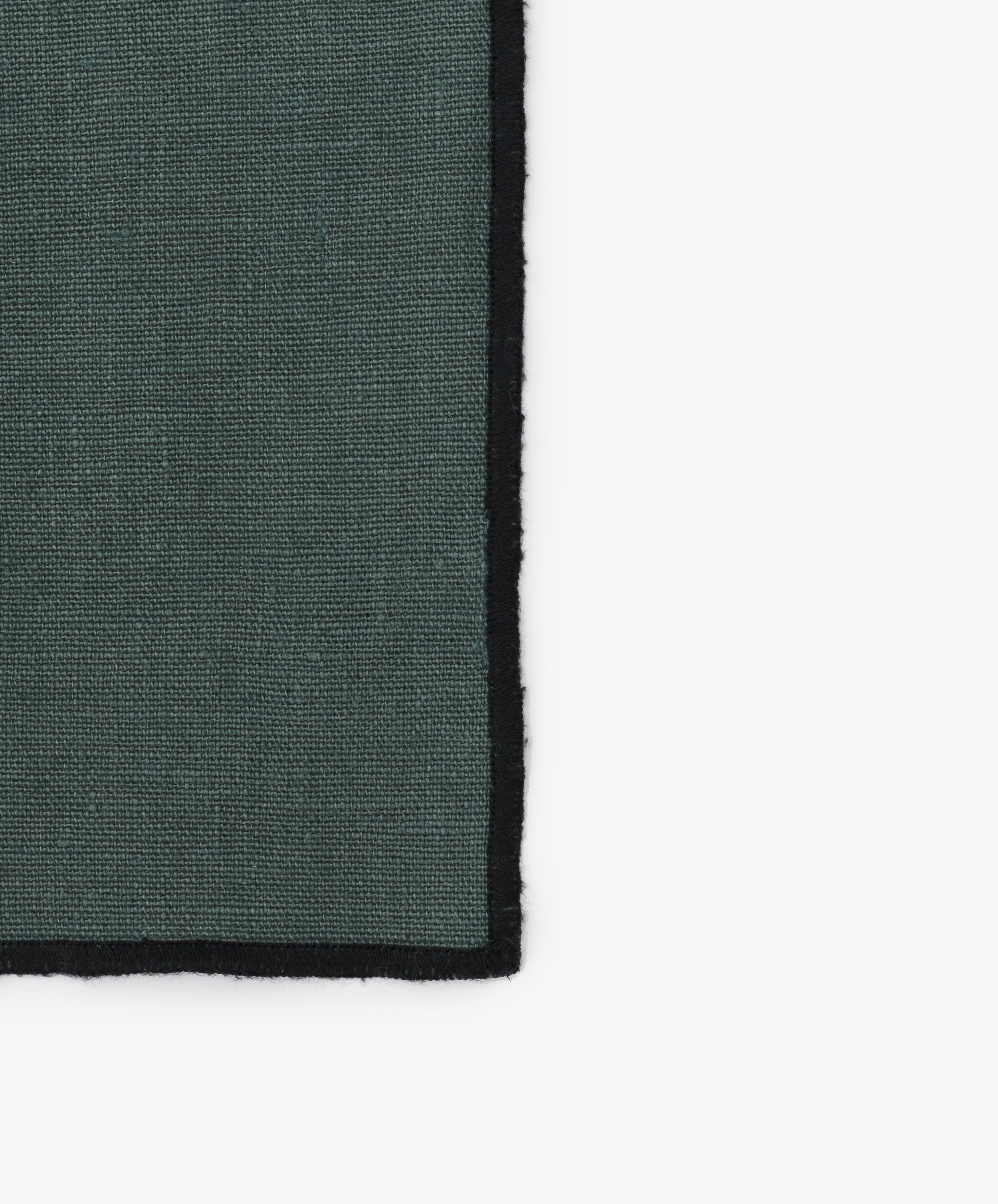 Close-up of black stitched edges on the grey-blue linen Luri Napkin.