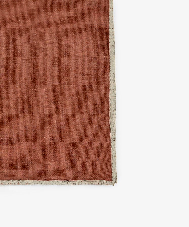 A close-up of the Corte Napkin, Set of 6, in rust linen-cotton blend with a beige fringed border, shown against a white background.