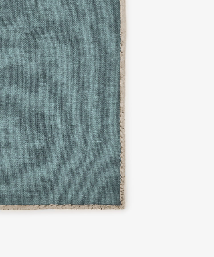 A set of six rectangular Corte napkins in teal linen with beige fringe borders is displayed on a white background, photographed from above. Their rich shades add elegance to any eco-friendly tableware setting.