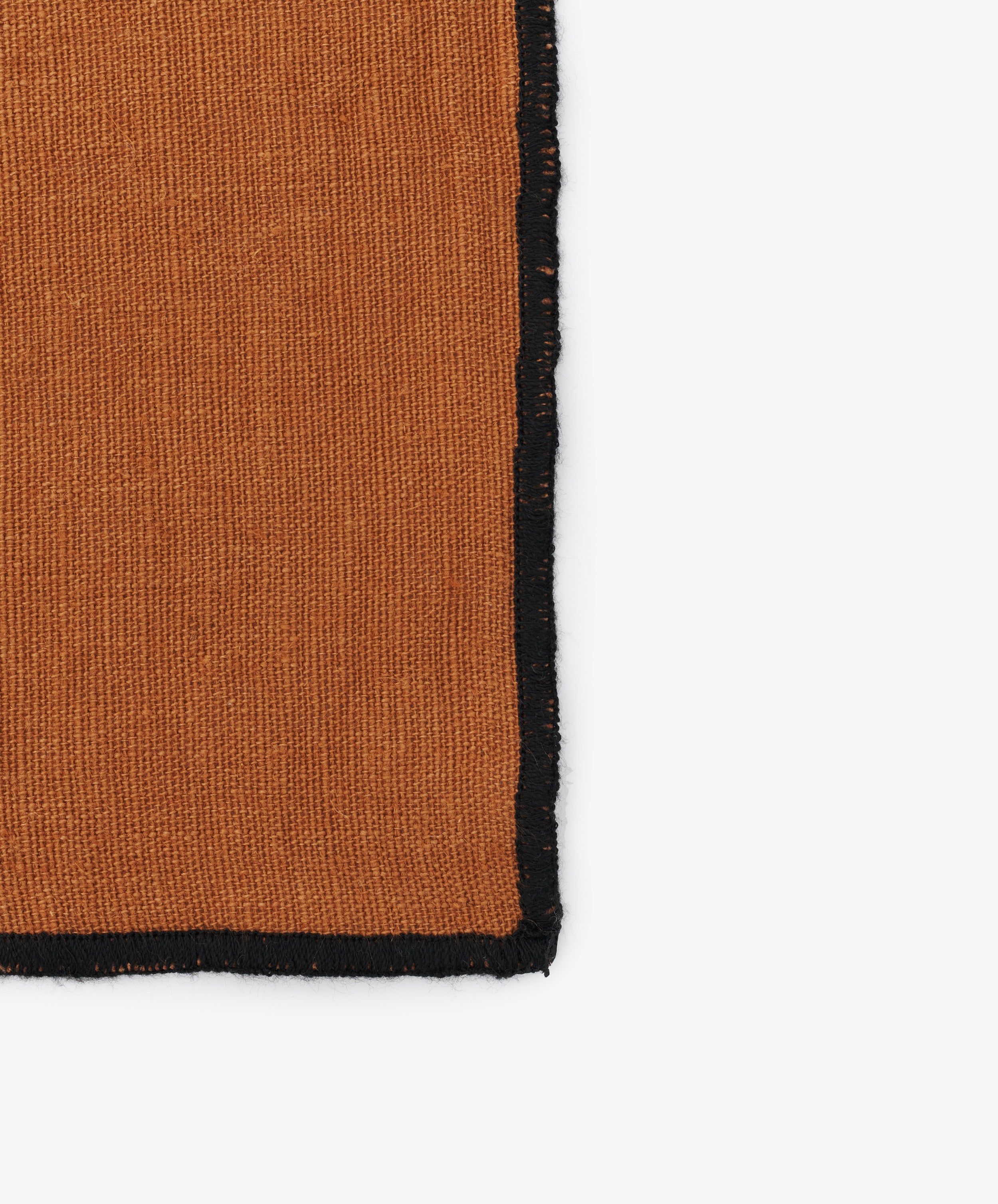 Close-up of black stitched edges on the caramel linen Luri Placemat.