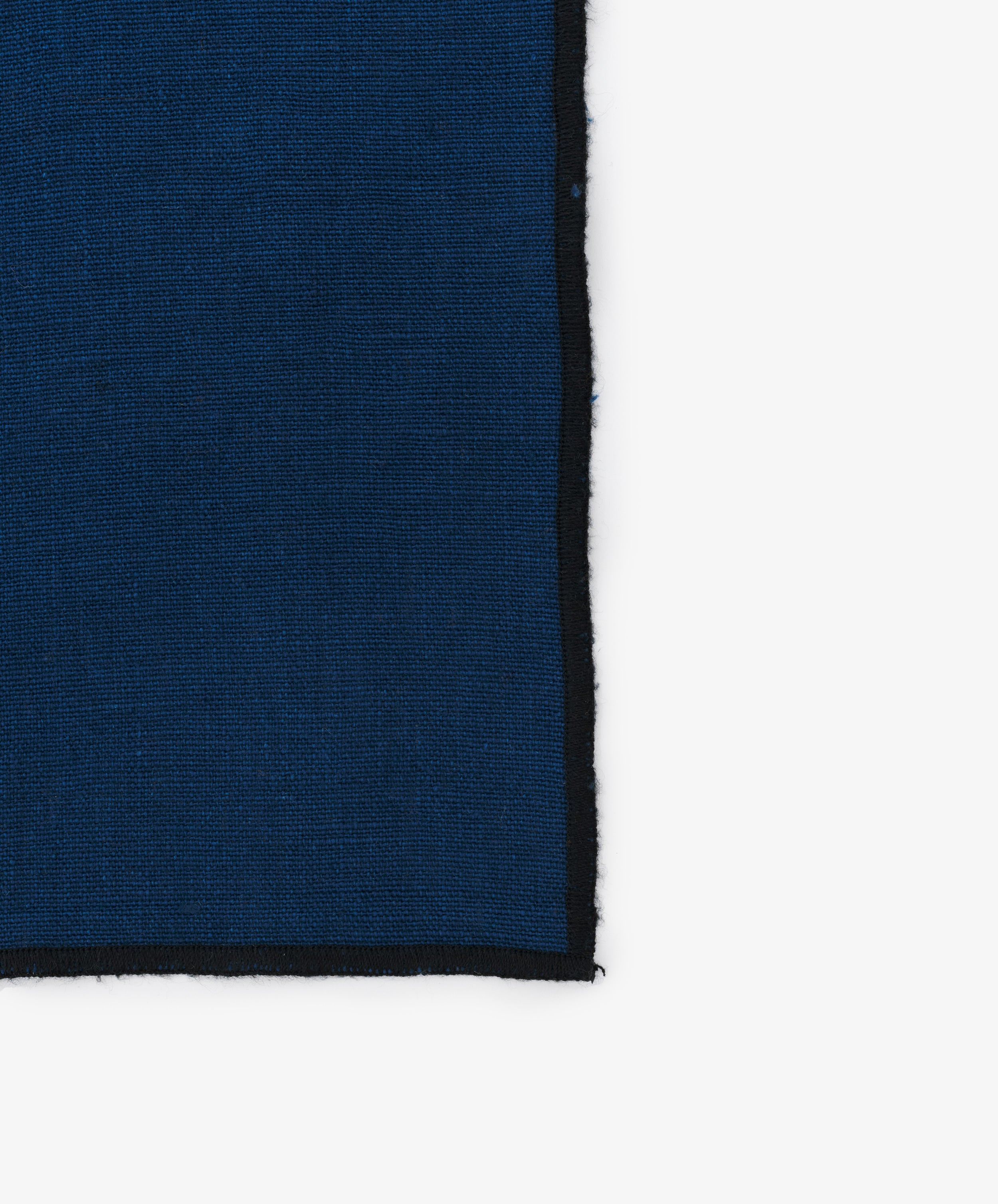 Close-up of black stitched edges on the blue linen Luri Placemat.