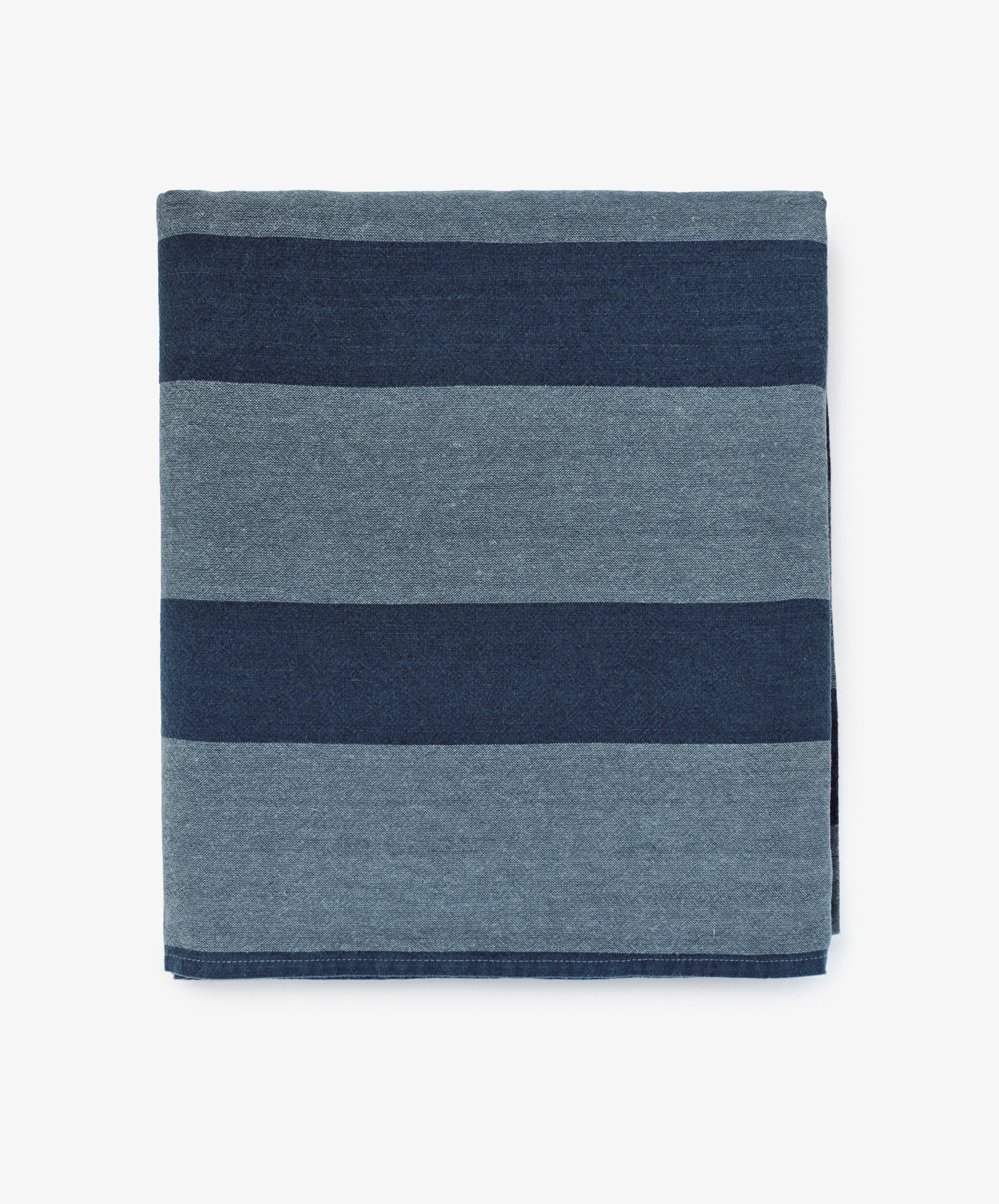 The Cruz Tablecloth features alternating wide dark blue and light blue stripes on white, crafted from washed linen and natural fibres for a soft, breathable feel.