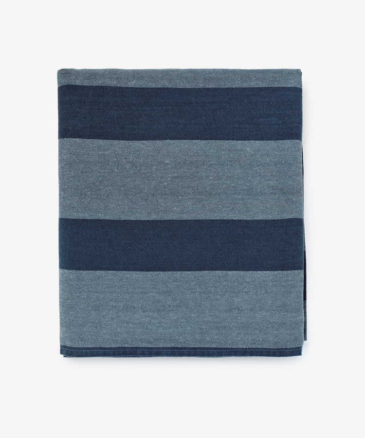 The Cruz Tablecloth features alternating wide dark blue and light blue stripes on white, crafted from washed linen and natural fibres for a soft, breathable feel.