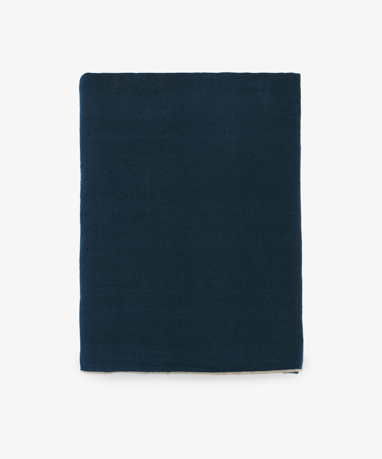 Venise Tablecloth. Folded rectangular dark blue linen cloth with cream stitched hem.