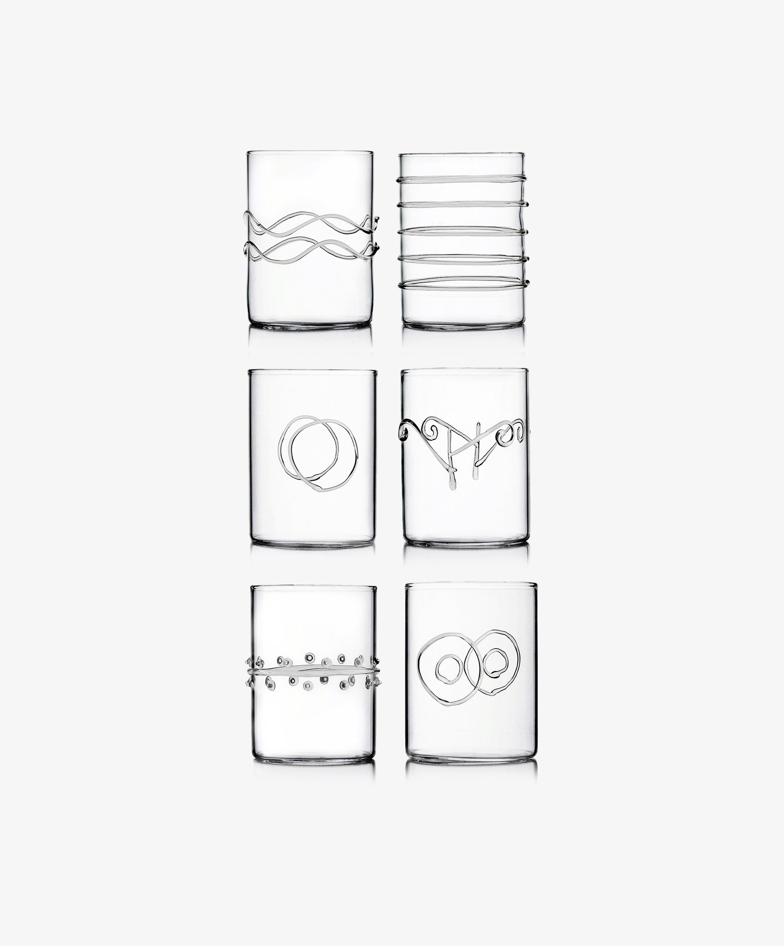 The Deco Shot Glass Set of 6 features clear glasses, each adorned with a unique minimalist silver wire design—arranged in two rows of three—ideal for serving grappa or limoncello with elegance.