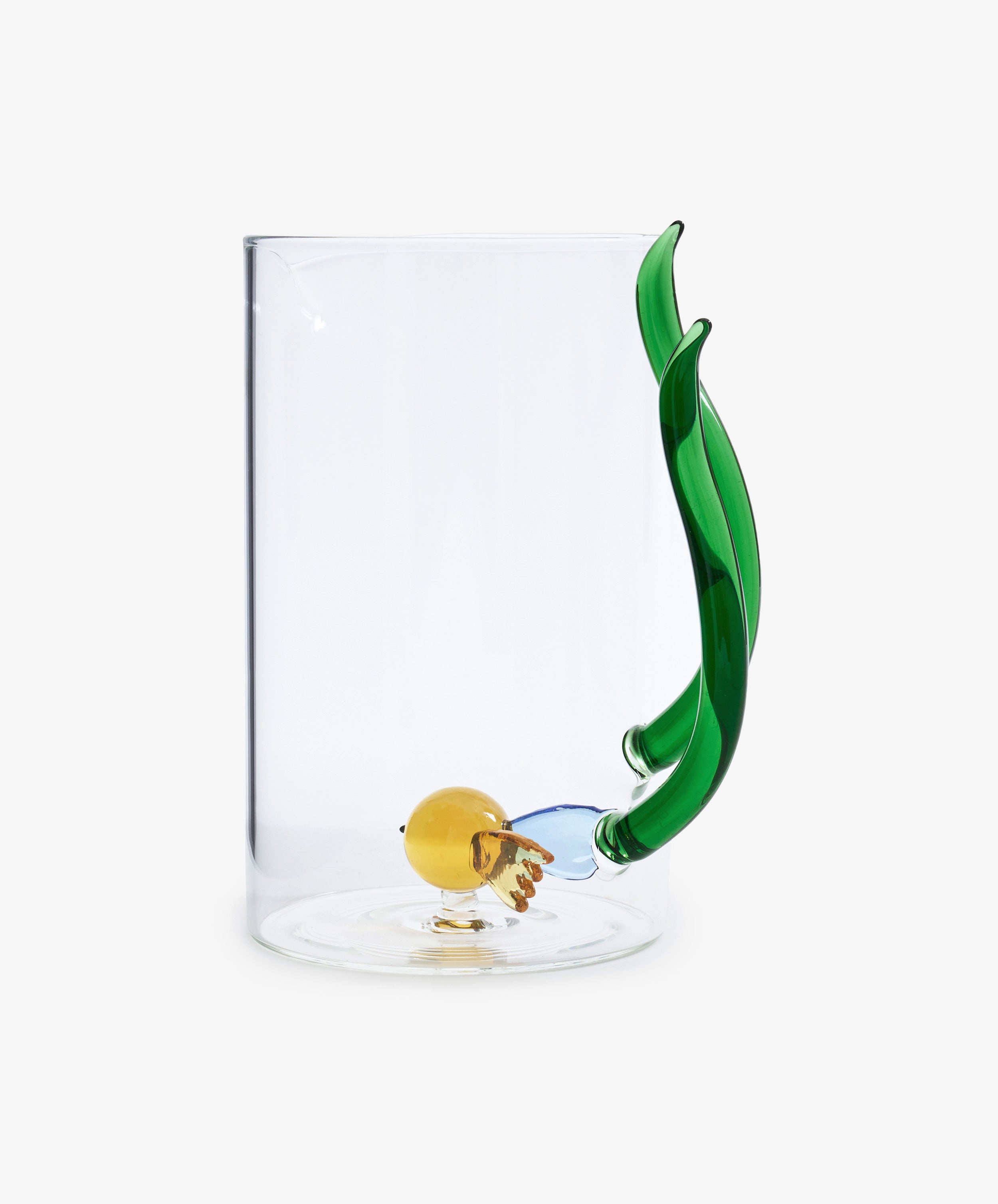 The Fish Pitcher is a clear borosilicate glass cup featuring a green curved handle and a yellow flower-like decorative element at the base.
