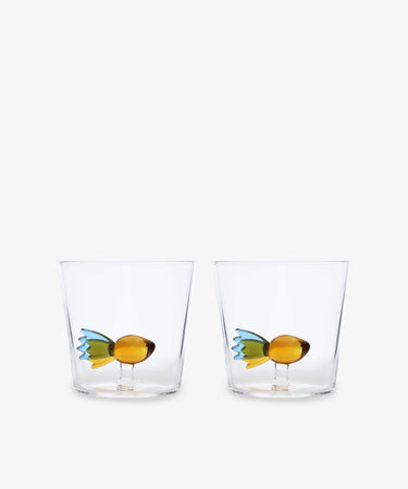 The Fish Tumbler, Set of 2, features handcrafted clear glass tumblers with decorative yellow and green fish figurines inside, showcasing Ichendorf Milano’s unique design against a plain white background.
