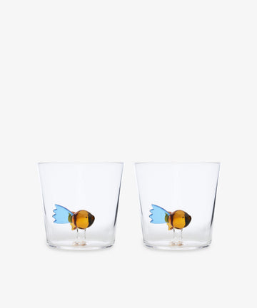 The Fish Tumbler, Set of 2 from Ichendorf Milano includes clear handcrafted glass tumblers, each with a colorful fish figurine at the bottom for a playful touch.