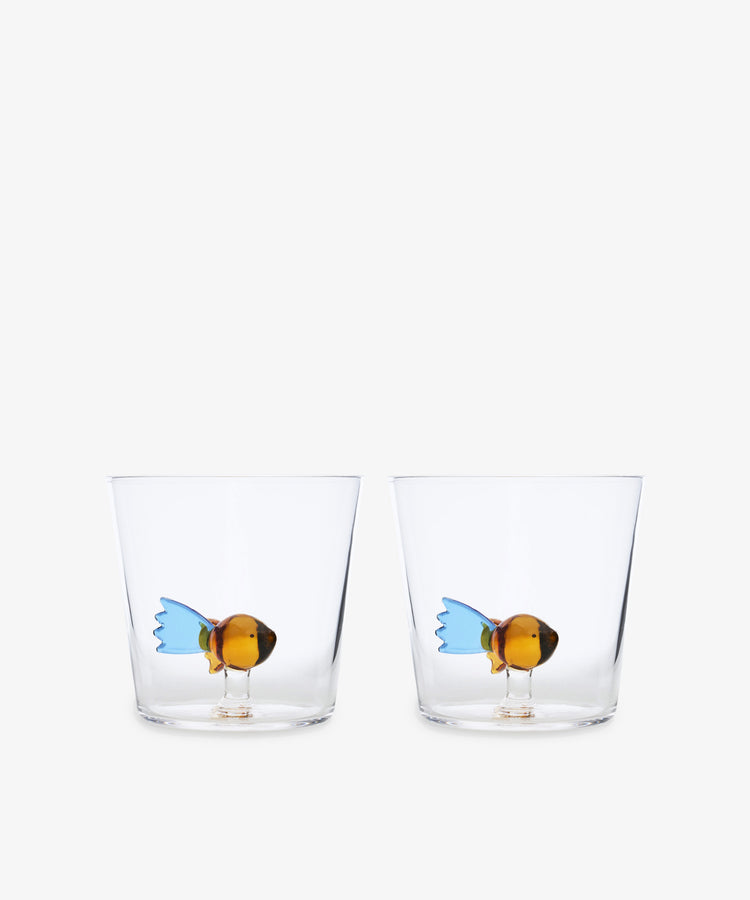 The Fish Tumbler, Set of 2 from Ichendorf Milano includes clear handcrafted glass tumblers, each with a colorful fish figurine at the bottom for a playful touch.