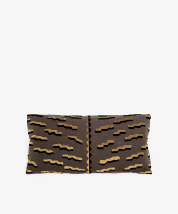 The Polo Lumbar Cushion is a rectangular pillow with a brown base and black, tan, and gold geometric zigzags, crafted from limited deadstock designer fabrics. Shown on a plain white background.