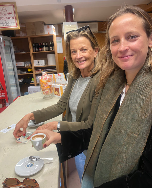 two woman having coffee smiling at camera