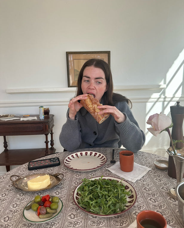 woman eating baguette sandwich at table