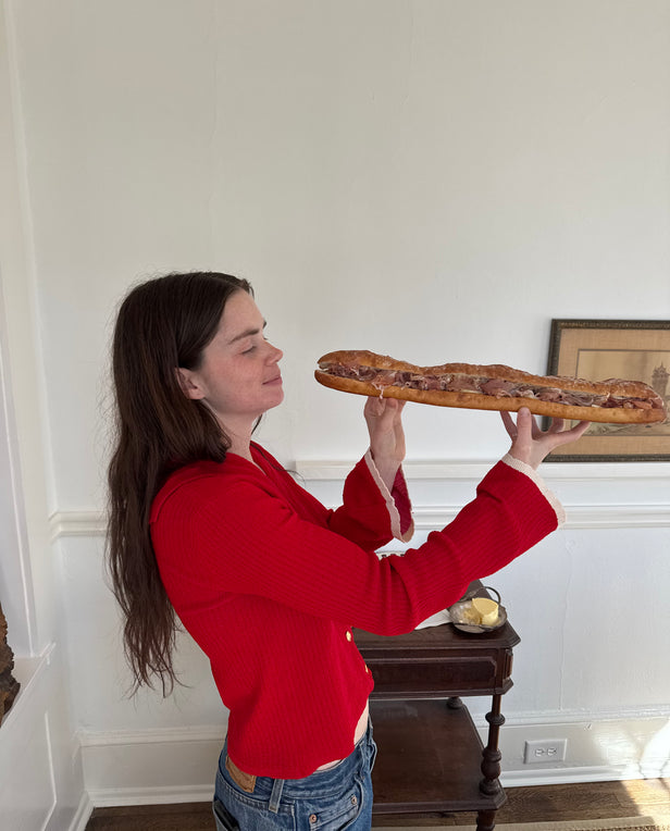 woman eating a long baguette sandwich