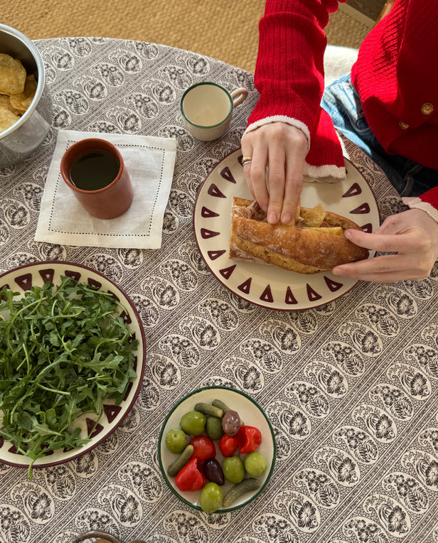 woman preparing sandwich at the table with salad and olives on the table