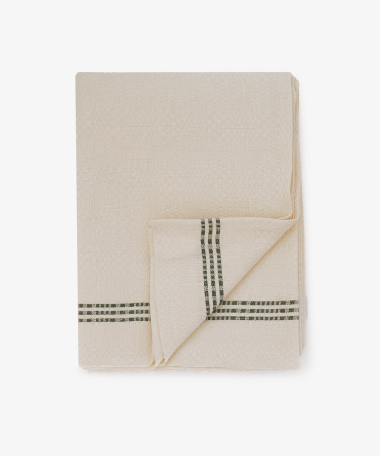 The Tilde Tablecloth, made from beige cotton linen with a textured DaldrÃ¤ll weave, features two intersecting dark green stripes and is shown against a white background.