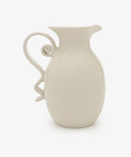 The Ola Vase is a white ceramic piece with a curved, decorative handle and spout, showcasing a minimalist silhouette against a plain white background.