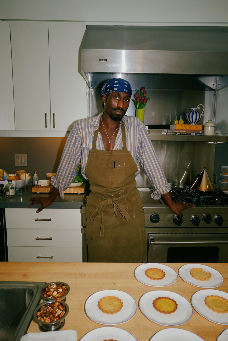 Person wearing an apron in a kitchen with food preparation on a counter