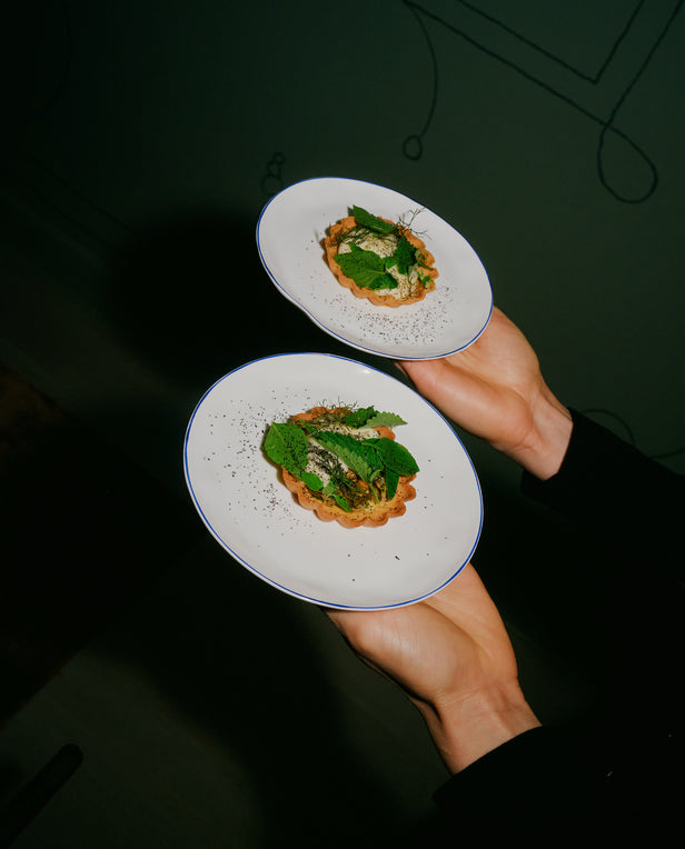 Two plates with food held by a person against a dark background