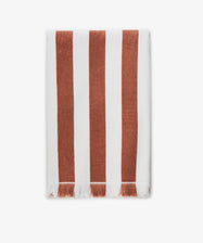 The Paloma Stripe Towel, crafted from striped cotton in bold brown and white verticals with a short white fringe along the bottom edge, evokes the relaxed elegance of the Italian coast.
