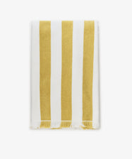The Citrino Stripe Towel is a rectangular Italian beach towel featuring vertical yellow and white stripes with tasseled edges, shown neatly folded on a white background.