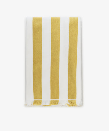The Citrino Stripe Towel is a rectangular Italian beach towel featuring vertical yellow and white stripes with tasseled edges, shown neatly folded on a white background.