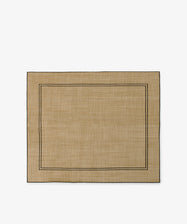 The Flavia Placemat, Set of 6, features rectangular beige raffia mats with a subtle woven texture and thin black borders near the edges—ideal for adding minimal elegance to your table.