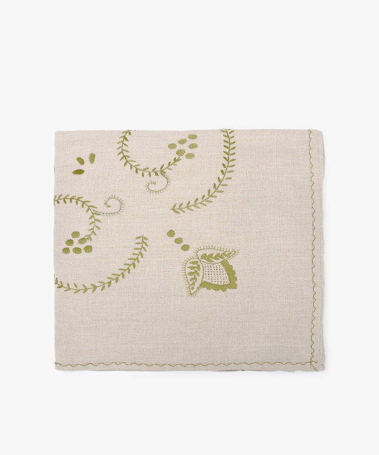 The Inez Tablecloth, crafted from Portuguese linen, is beige with green embroidered floral and leaf designs and finished with elegant scalloped edges.