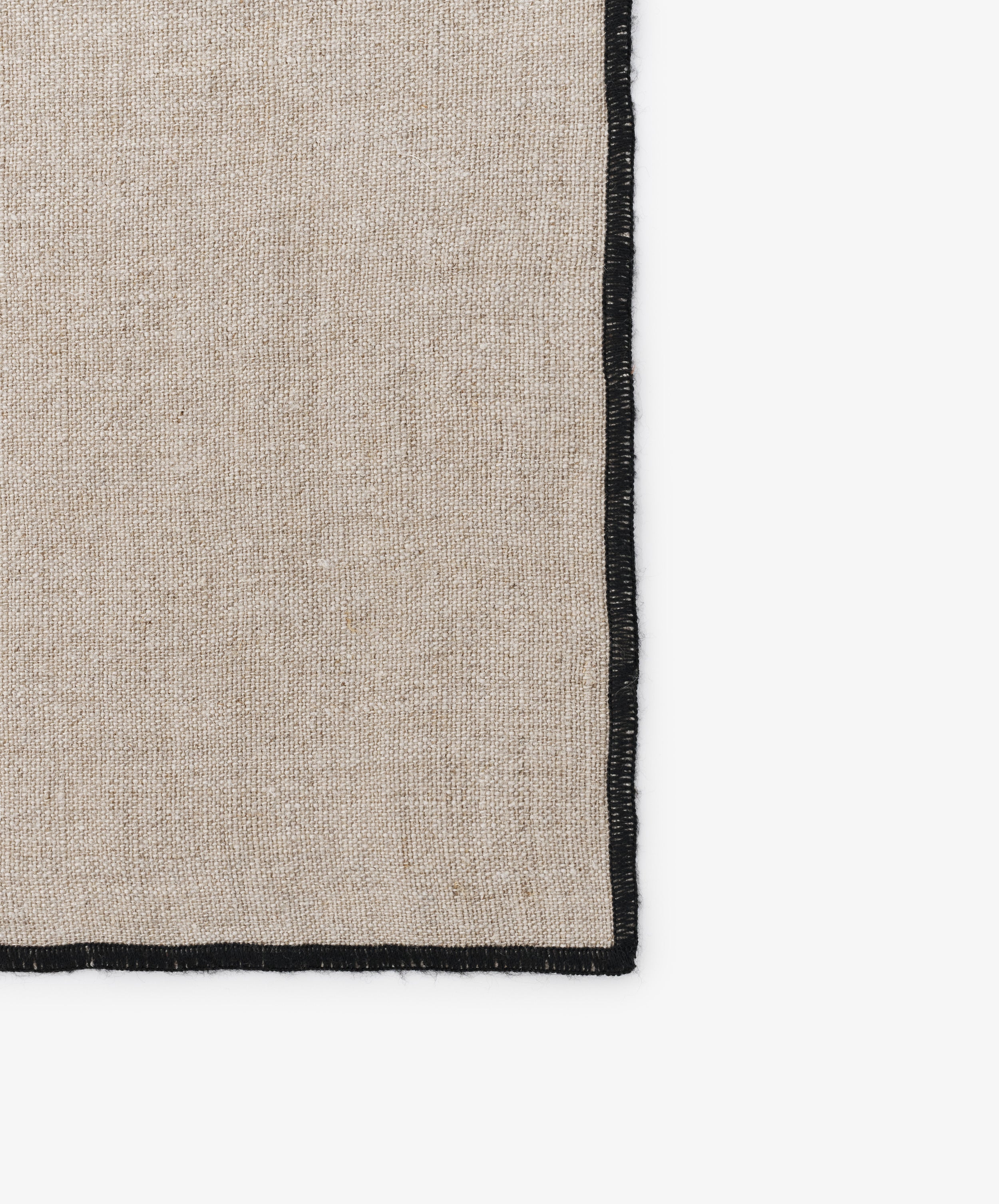 Close-up of black stitched edges on the natural linen Luri Placemat.