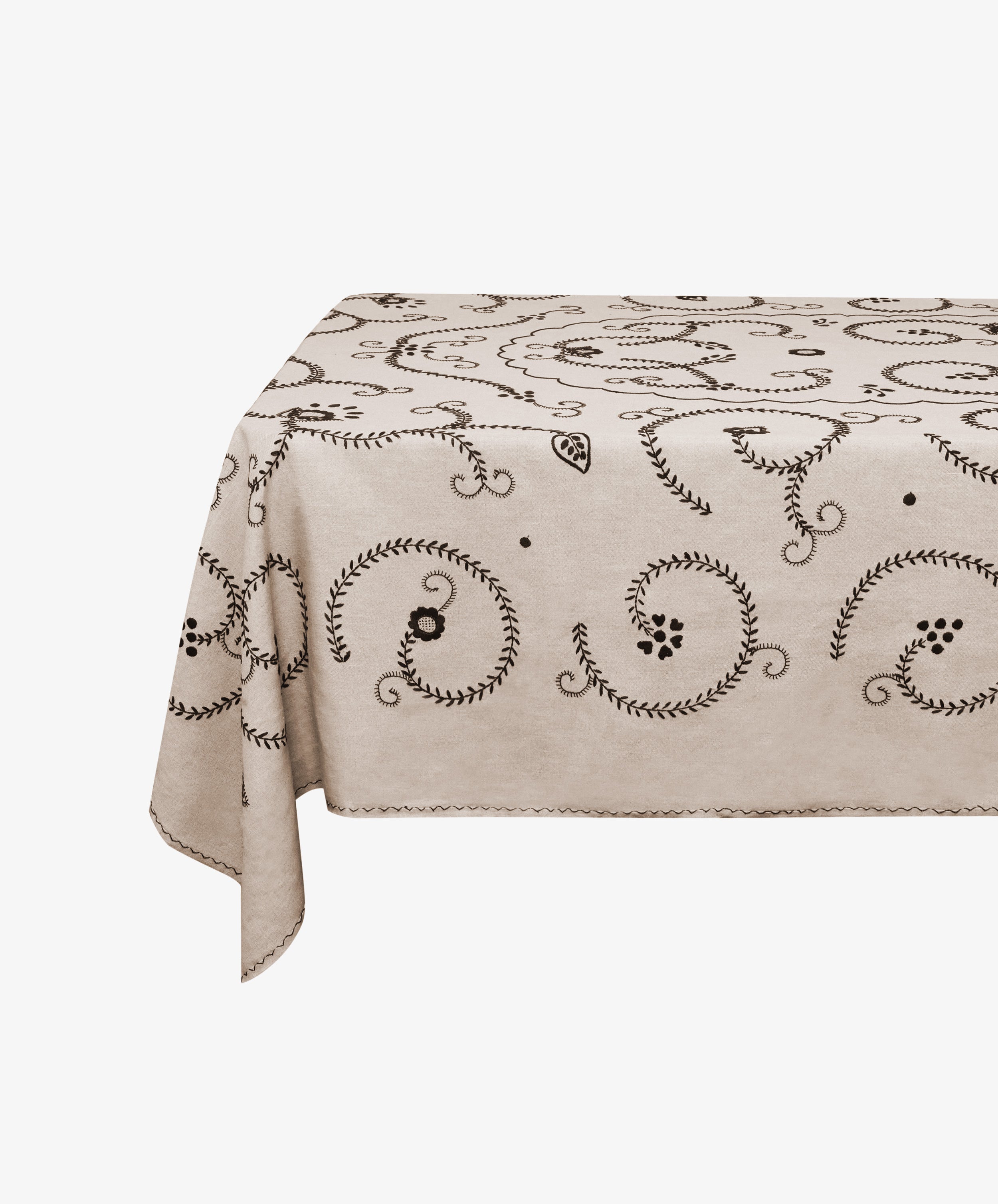 Tan cotton Inez Tablecloth with black embroidery spread and draped over invisible table.