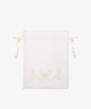 The Linen Drawstring Bag is handmade in Portugal from white linen, with cream Viana do Castelo embroidery and ribbon ties. Shown flat on a plain light background.