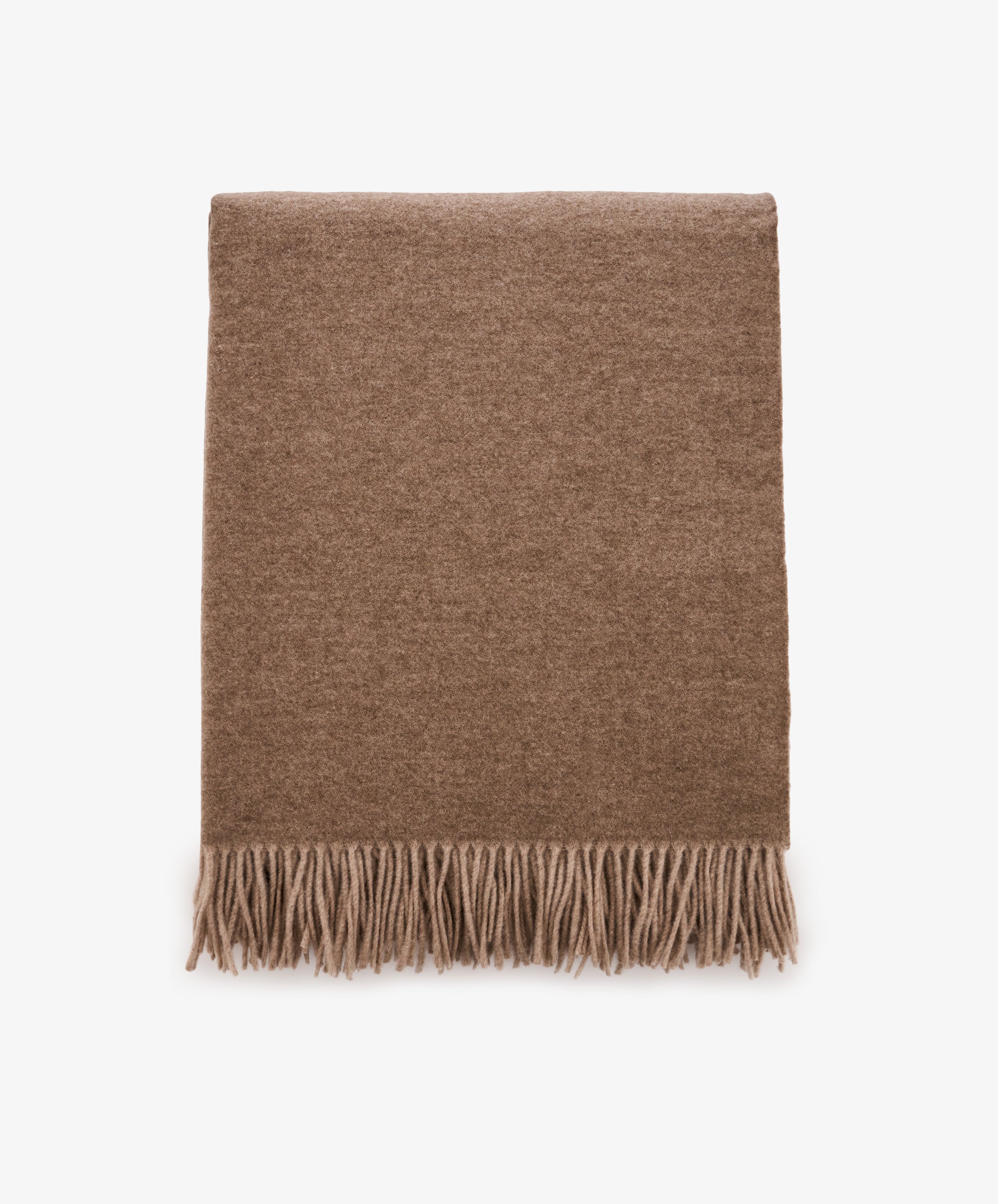 Folded Ulisse Throw in neutral beige merino wool with fringe detailing along the bottom edge, shown on a plain white background.