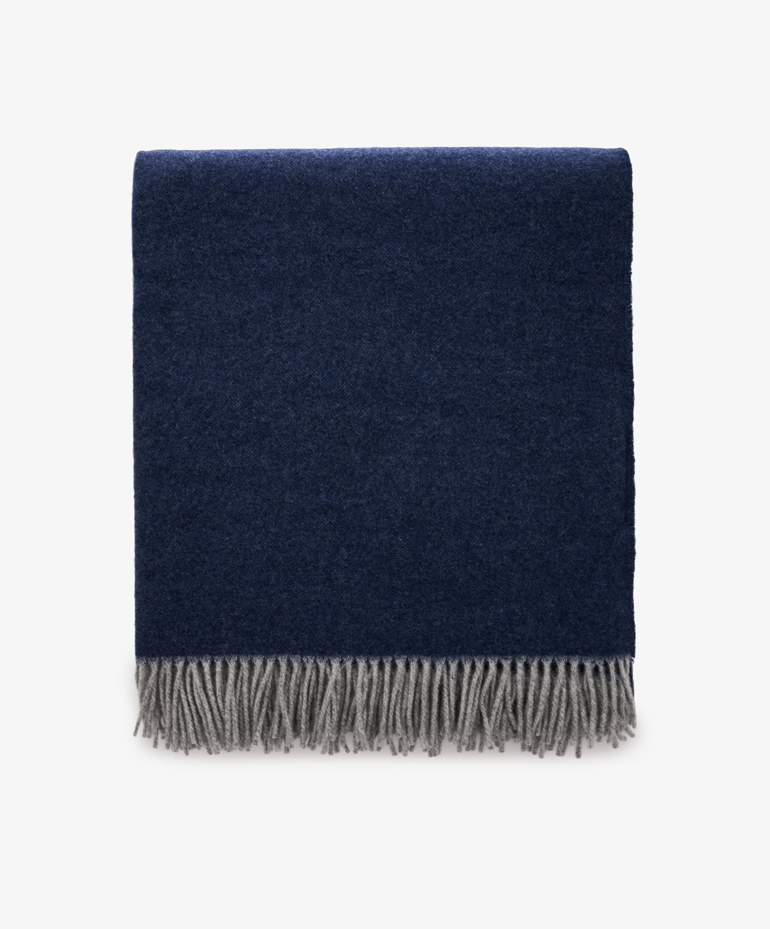 The Ulisse Throw, in oceanic blue with a gray fringe, is neatly folded and displayed against a plain white background.