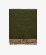 A folded Ulisse Throw in forest green with beige fringe along the bottom edge, displayed on a white background.