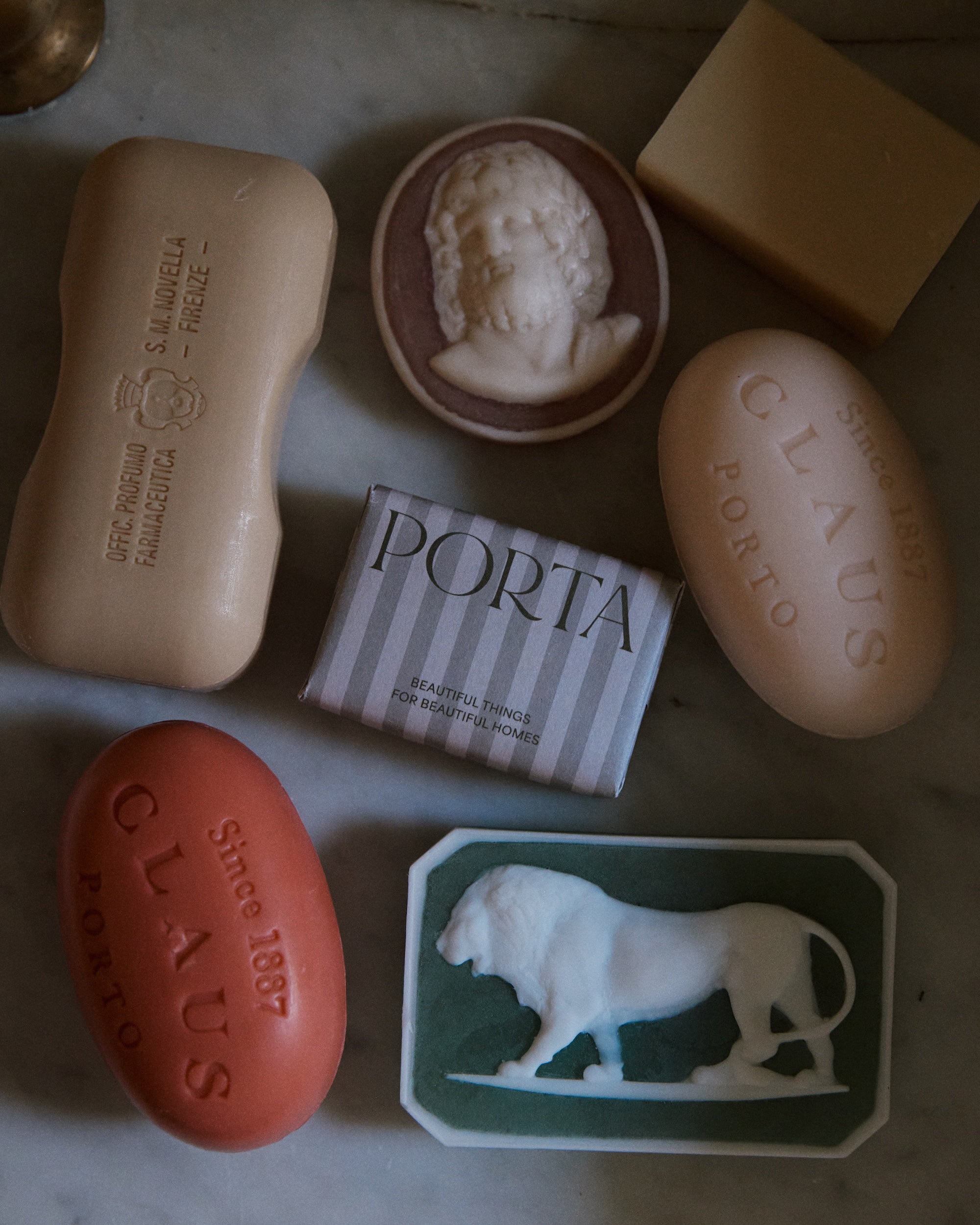 Hercules Soap offers decorative and sculptural bars in oval, rectangular, and unique shapes, beautifully arranged on a marble surface.
