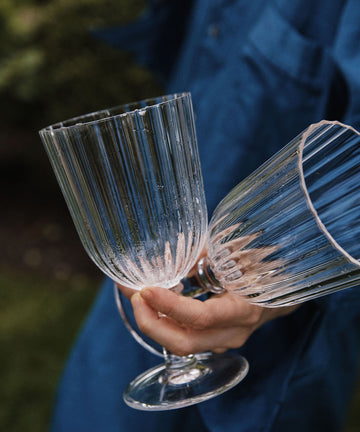 Someone in a blue shirt holds two Fresco Goblets from the Set of 4 outdoors.
