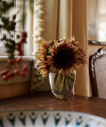 The Gem Bud Vase with sunflowers sits on a wooden table in gentle light near a patterned bowl, evoking the charm of the South of France.