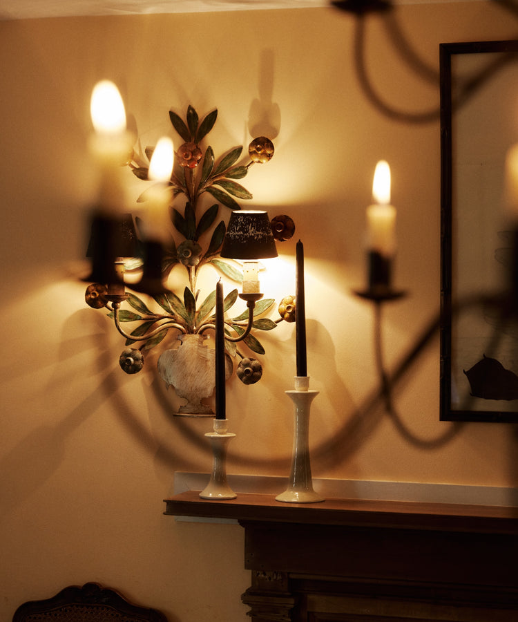 Two Tapered Candles, Set of 2 in white holders on a mantel, with glowing wall sconces adding warm light to a softly decorated room.
