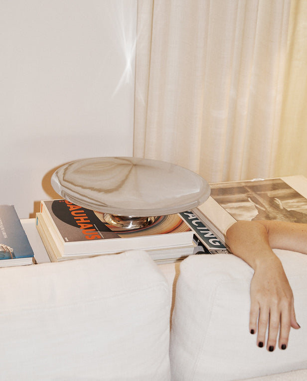 Person lying on a couch with a marble-patterned ottoman and books on a coffee table.