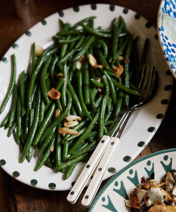 Serve green beans garnished with garlic on the Nina Oval Serving Platter—an essential, hand-glazed ceramic piece with two stylish serving utensils.