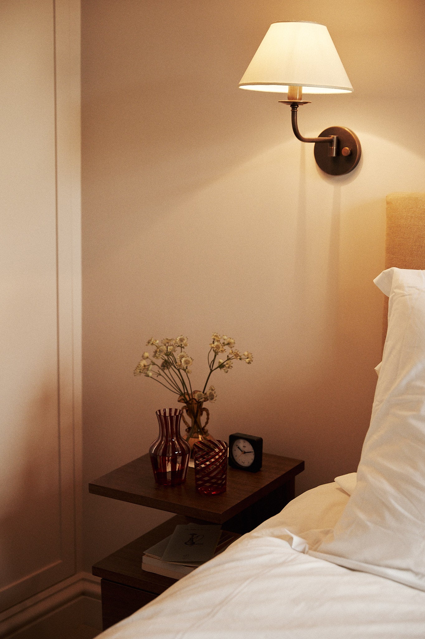 Bedroom scene with a nightstand, lamp, and decorative items.