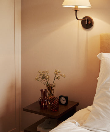 Bedroom scene with a nightstand, lamp, and decorative items.