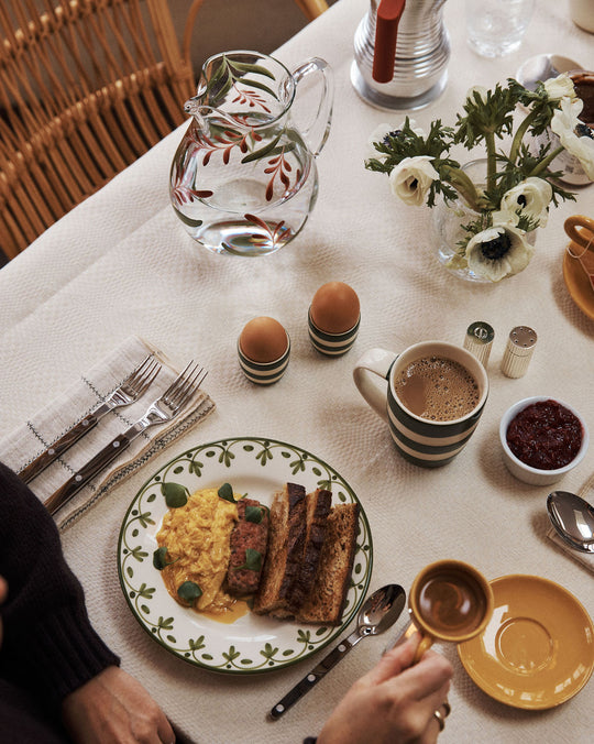 Breakfast table setting with a plate of food, coffee, and utensils.
