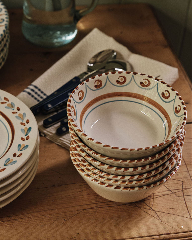 Ottoline Cereal Bowls, sold as a set of 4, are arranged on a wooden table beside cutlery, a folded cloth, and a glass pitcher of water.