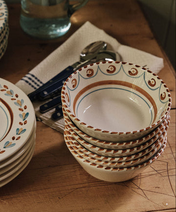 Ottoline Cereal Bowls, sold as a set of 4, are arranged on a wooden table beside cutlery, a folded cloth, and a glass pitcher of water.