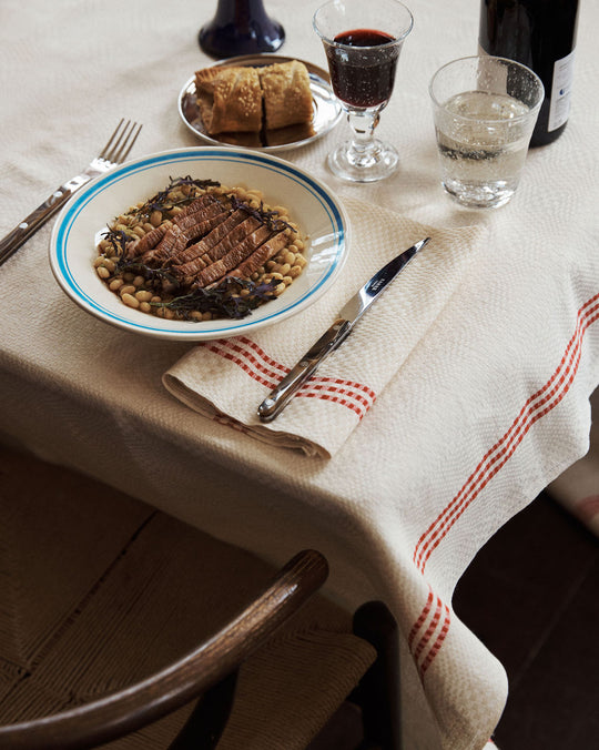 Dinner table setting with a plate of food, cutlery, and drinks on a checkered tablecloth.