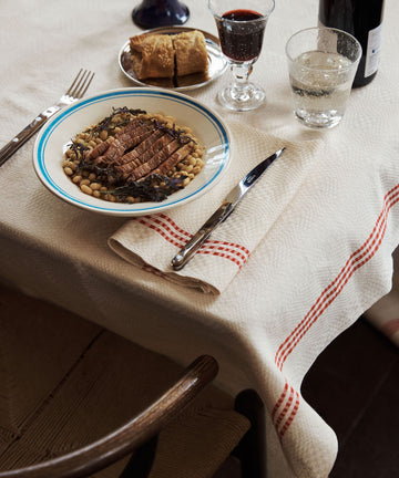 Dinner table setting with a plate of food, cutlery, and drinks on a checkered tablecloth.
