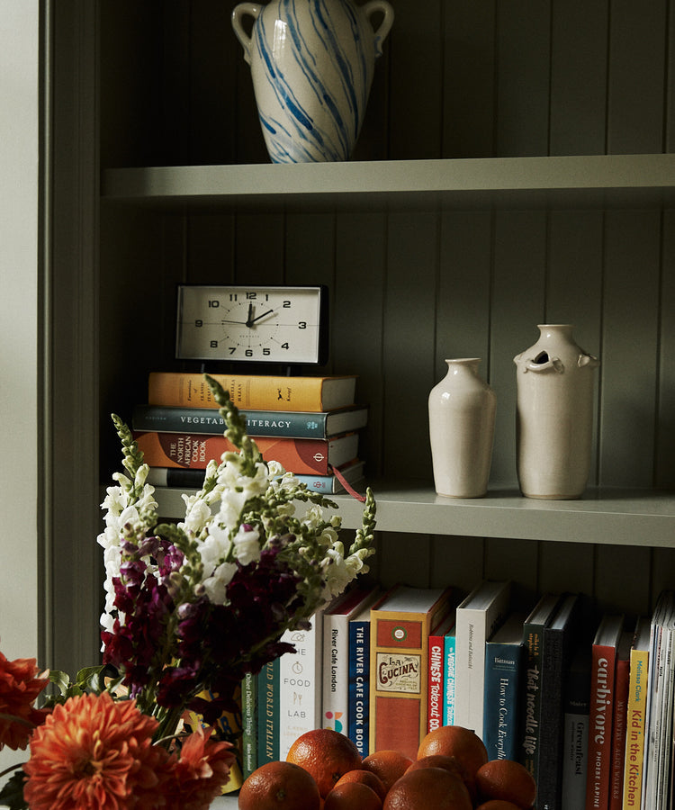 Bookshelf with decorative items including vases, a clock, and a bowl of fruit.