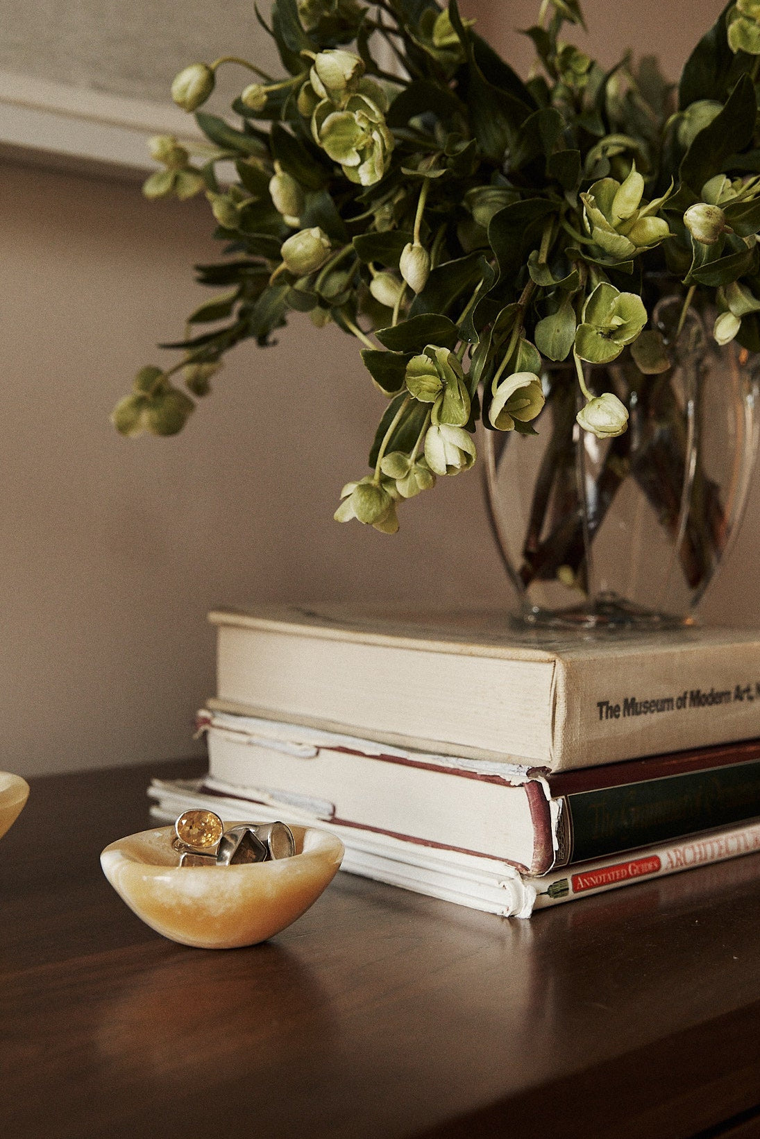 Vase with greenery on top of books on a wooden surface