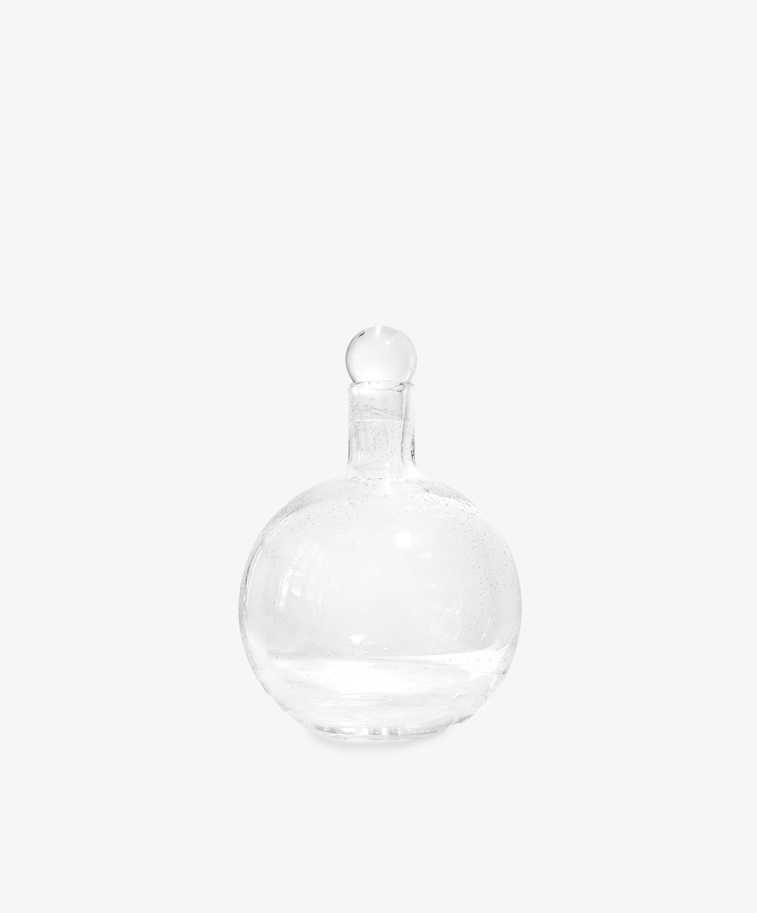 The Bubble Glass Carafe features a clear, round design with a narrow neck and matching glass stopper, displayed against a plain white background.