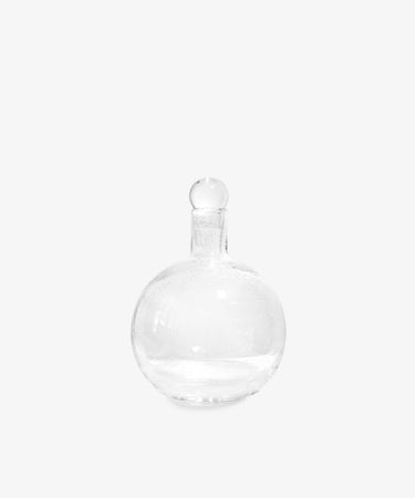 The Bubble Glass Carafe is a hand-blown, clear glass round bottle with a matching glass stopper from the S.R. Collection, shown against a plain white background.